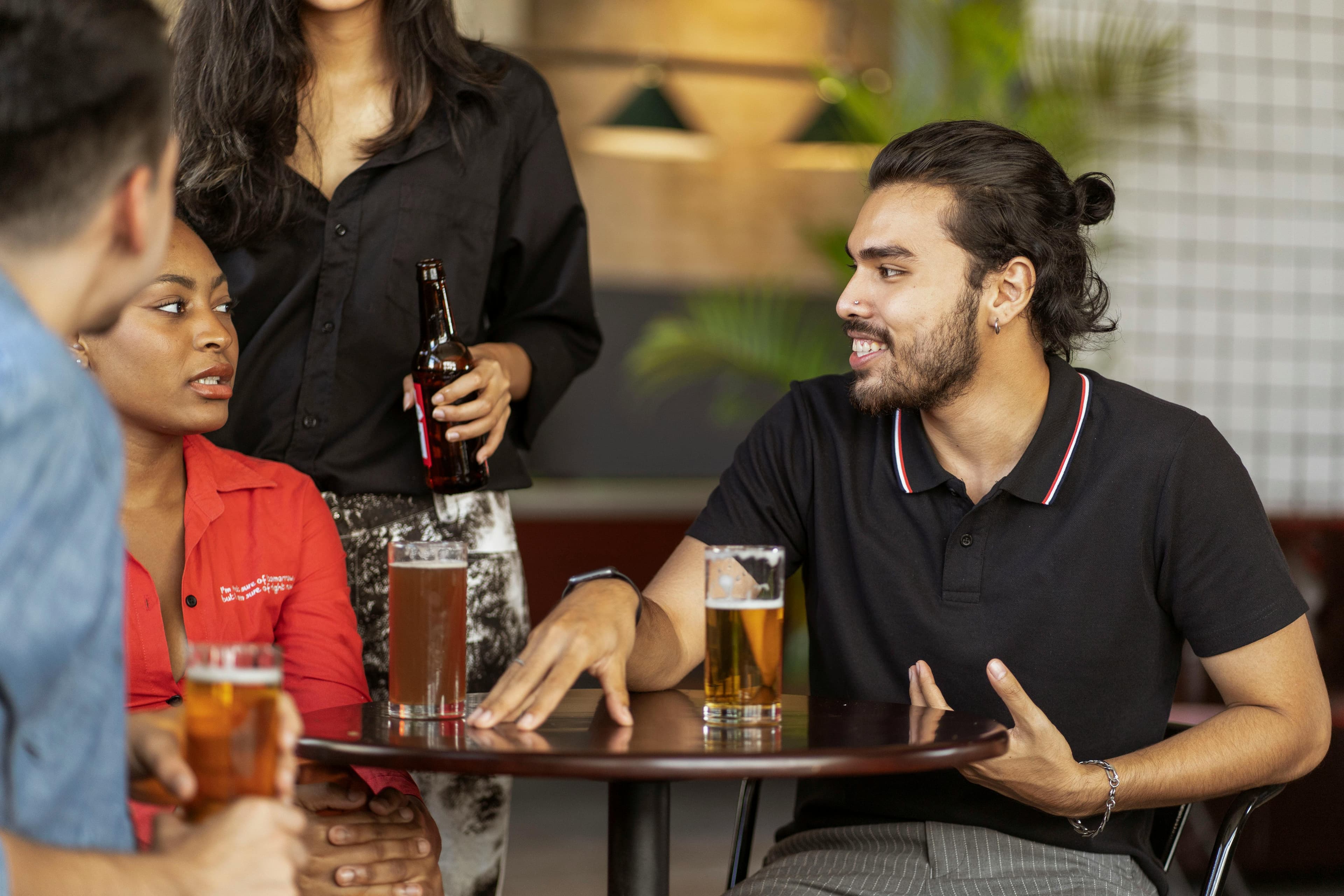 A small crew gathered round a pub table, mid-conversation, drinks in hand